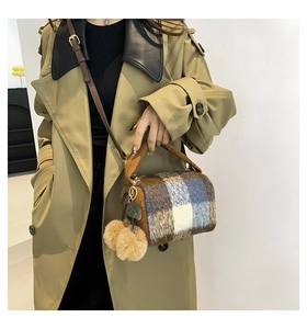 Side view of model wearing a plaid plush Boston bag with corduroy handle and pom-poms