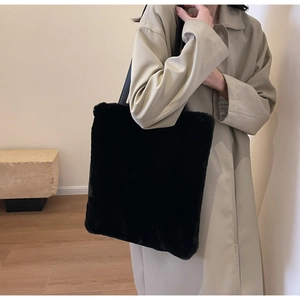 Gros plan d'un cabas noir en peluche avec sangle en cuir sur un trench-coat beige