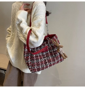 Detail of red tweed tote bag with shoulder strap and cute rabbit charm on white sweater