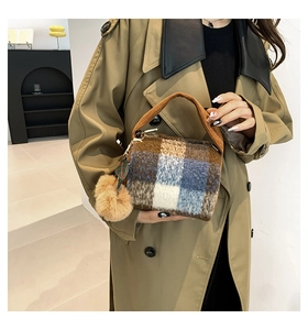 Detail of wool-like plaid Boston bag with plush pom-pom and arched brown handles