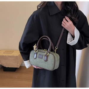 Dettaglio della borsa Boston vintage in tela oliva con manici in pelle e finiture oro