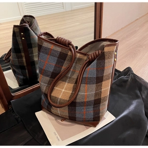 Detail der karierten Beuteltasche mit gedrehten Ledergriffen und goldener Nietverzierung