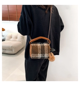 Detail of plush brown plaid Boston bag with fur ball charm and corduroy handle strap