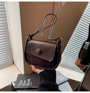 Detail of vintage saddle bag featuring brown leather and checkered tweed fabric texture