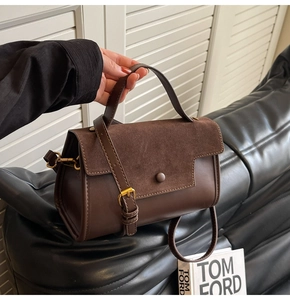 Detail of dark brown leather handbag with suede flap, gold buckle and adjustable strap