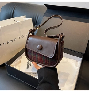 Close-up of retro plaid wool handbag with brown leather flap in premium gift box packaging