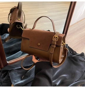 Detail of a brown vintage tote bag showing texture contrast and bronze hardware