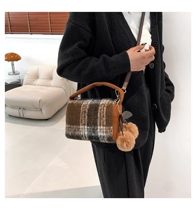 Detail of plush plaid Boston bag with corduroy handles and decorative fuzzy pompom charms