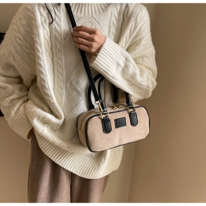 Dettaglio borsa Boston scamosciata beige con manici in pelle nera e logo impresso