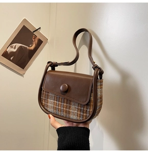 Detail of vintage brown plaid wool saddle bag with leather flap and button