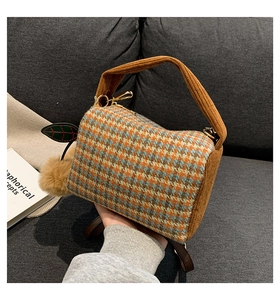 Detail of autumn houndstooth Boston bag featuring corduroy handles and plush charm