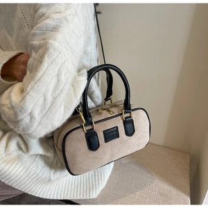 Dettaglio borsa boston in pelle scamosciata beige con finiture in pelle nera e tracolla