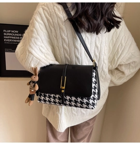 Detail view of houndstooth crossbody bag with plush rabbit charm on a female model