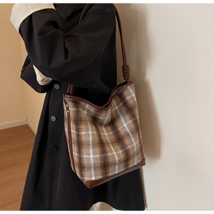 Details der karierten Beuteltasche mit braunem Lederbesatz und Knotenschultergurt