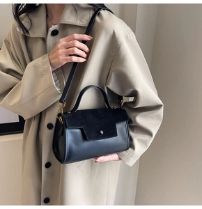 Chic black flap crossbody bag worn by a model in a beige trench coat for a trendy look