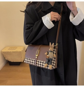 Detail of checkered tote bag with golden lock and cute rabbit plush charm decoration