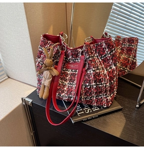 Detail of red tweed tote bag featuring leather logo patch and cute bunny charm accessory