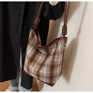 Detail der Vintage-Karo-Beuteltasche mit braunen Lederriemen und Knotenakzenten