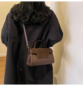 Detail view of model wearing a vintage dark brown crossbody bag on a black coat