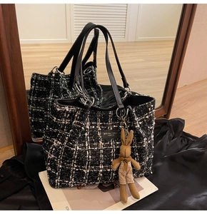 Detail of checkered tweed tote bag with a cute rabbit charm and leather brand logo