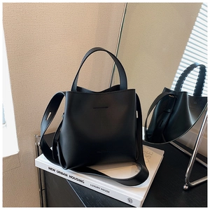 Borsa a secchiello moderna nera opaca su consolle con riflesso a specchio e dettaglio logo