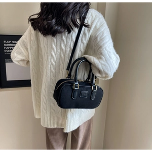 Dettaglio di una borsa Boston nera opaca con zip dorata indossata da una modella in maglia