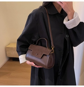 Detail of dark brown leather and suede crossbody bag with elegant gold hardware