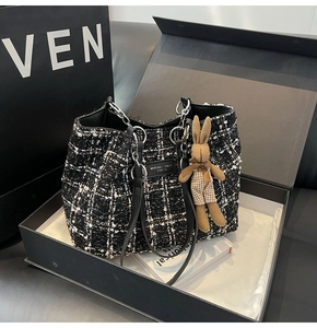 Detailed shot of black and white tweed tote bag with chain strap and plush bunny charm