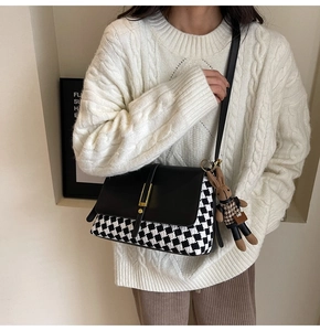 Detail of checkered tote bag with gold metal lock and cute rabbit doll keychain charm