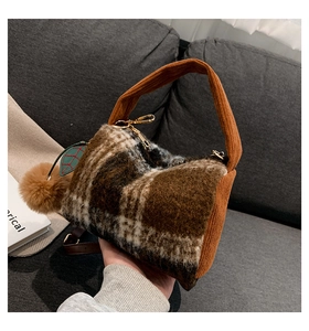 Close-up of fuzzy checkered Boston bag featuring corduroy handles and plush charm detail