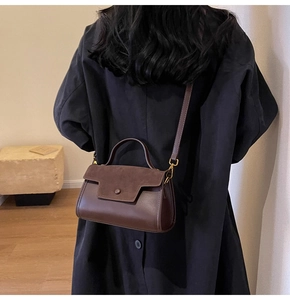 Detail of dark brown leather crossbody bag featuring mixed suede textures and round clasp