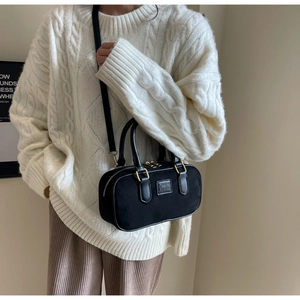 Dettaglio borsa a tracolla nera opaca con finiture dorate e logo ORN ORN su maglia