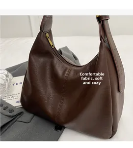Detail view of a soft brown leather tote bag with pleated texture and wide strap