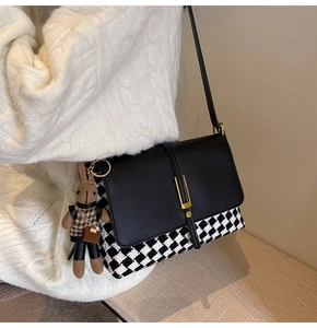 Detail of crossbody bag with black white houndstooth pattern and a plush bunny charm