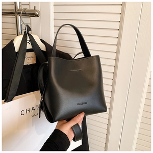 Dettaglio della borsa a secchiello minimal in pelle nera con manico largo e logo goffrato