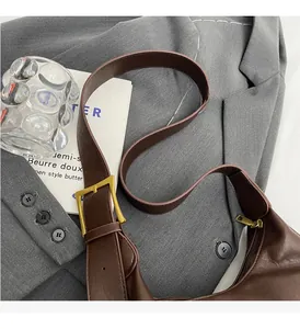 Macro shot of dark brown leather tote bag featuring gold hardware on a grey blazer