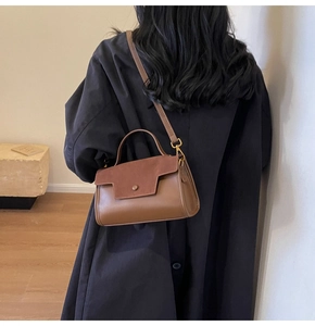Detail view of the brown vintage crossbody bag with a textured flap and smooth leather body