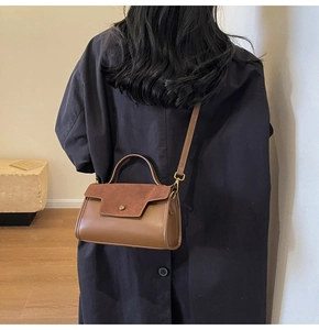 Rear view of a model in a black coat holding a brown dual-texture vintage handbag
