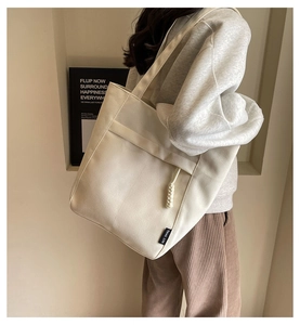 Bolso tote de lona con bolsillo delantero mostrado en un estilo casual para el diario