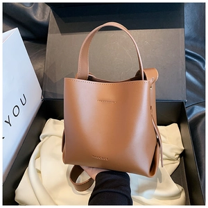 Dettaglio di una borsa a secchiello in pelle marrone con logo e tracolla rimovibile