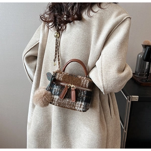 Detail van wollen plaid mini box tas met gouden ketting en pluche pompon hanger