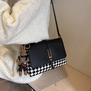 Chic houndstitch tote bag with metallic clasp and bunny charm worn on white knit sweater