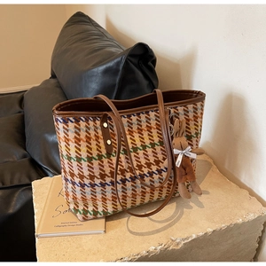 Detail of multi-color houndstooth tote bag with brown leather handles and rabbit charm