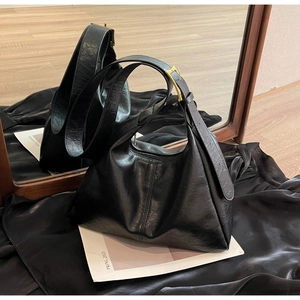 Detail of black matte leather hobo bag with gold adjustable buckle on shoulder strap