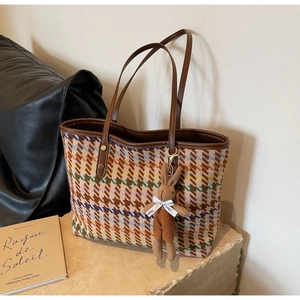 Detailed close-up of colorful houndstooth tote bag with leather handle and rabbit charm