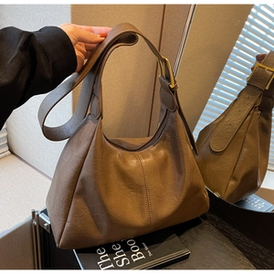 Detail of adjustable strap and golden buckle on brown leather hobo shoulder bag