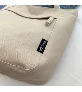 Detalle de la tela de lona del bolso tote con etiqueta tejida y costuras reforzadas