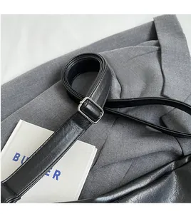 Adjustable black leather shoulder strap with silver buckle and fine edge stitching detail
