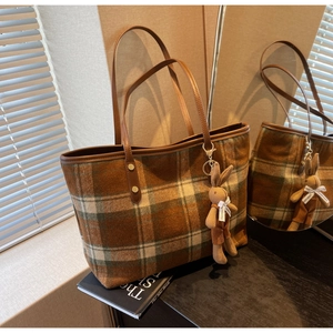 Detail of checkered wool tote bag with brown leather straps and cute bunny charm