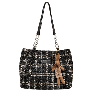 Black and white tweed tote bag with leather straps and a cute rabbit charm on white background
